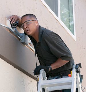 installation cam1 A technician adjusting a security camera while installing the system to the exterior of a building.